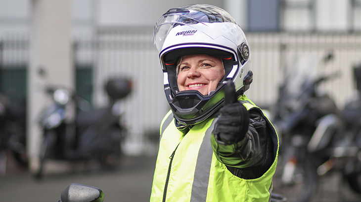 A female rider wears a helmet, gloves, jacket and hi-vis vest.