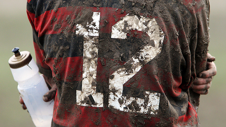 Muddy rugby player with drink bottle